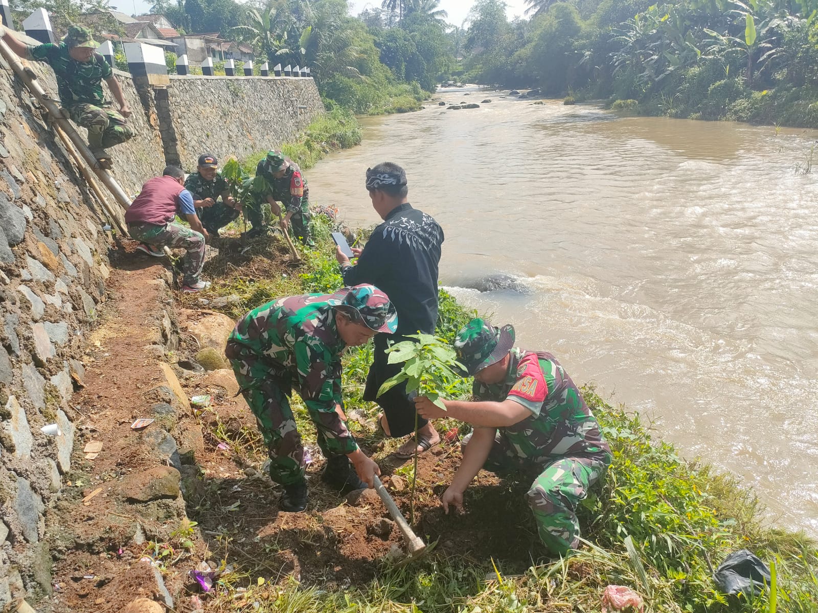 Personel Kodim 0607/Kota Sukabumi bersama dengan aparat pemerintahan setempat melaksanakan penanaman pohon dan bersih-bersih bantaran Sungai Cimandiri, pada Sabtu, 2 Desember 2023. Foto: Humas Kodim/0607 Kota Sukabumi for HALOSMI.