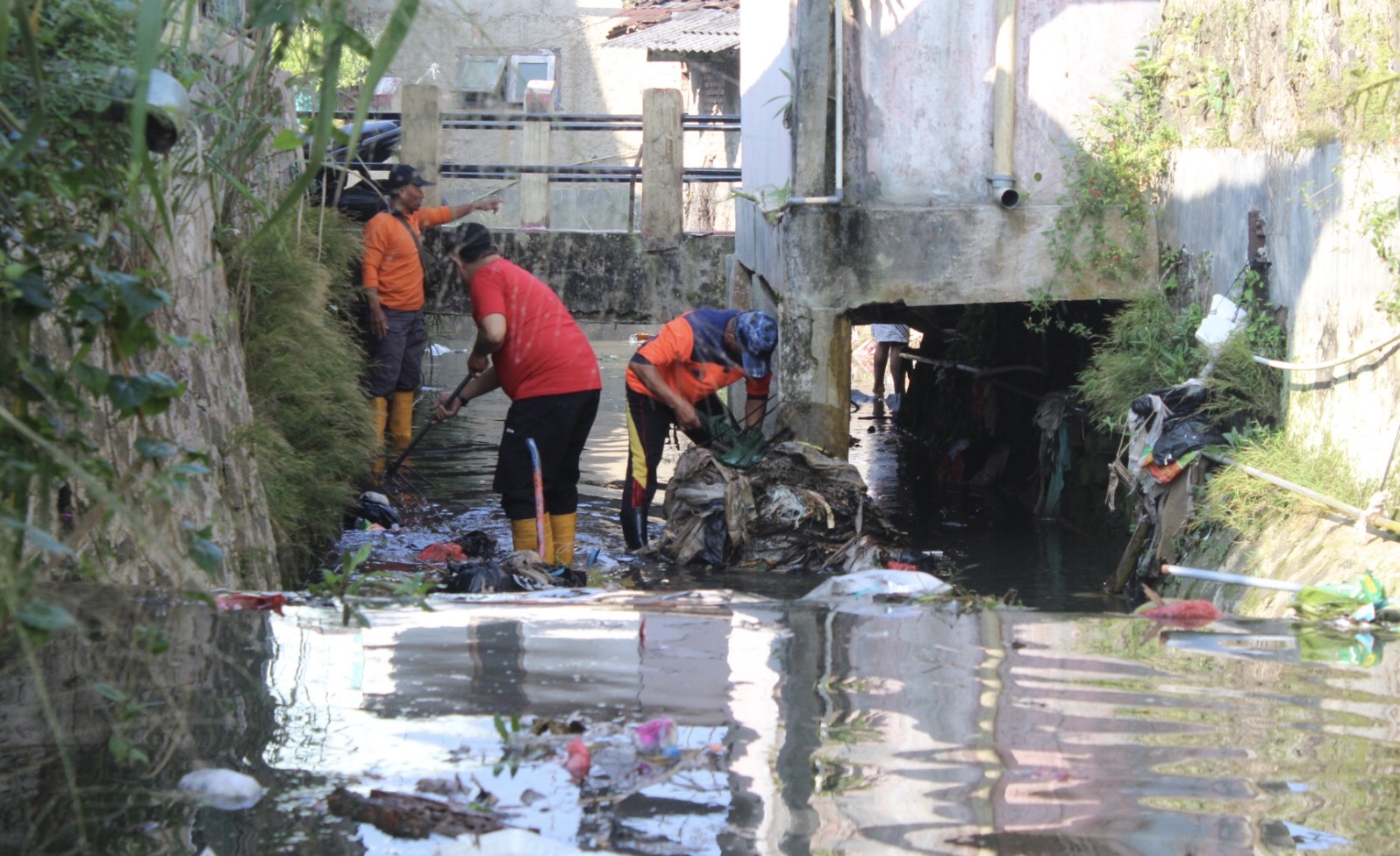 Petugas bersama warga melaksanakan kerja bakti membersihkan sampah di salurah air di Kampung Kebon Kalapa, RT 05/10 Kelurahan Kebonjati, Kecamatan Cikole, Kota Sukabumi, pada Jumat, 21 Juni 2024. Pusdalops BPBD Kota Sukabumi for HALOSMI.