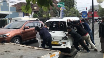 Sejumlah warga tengah berupaya mengevakuasi satu unit angkot yang terlibat kecelakaan di ruas Jalan Suryakencana, Kecamatan Cikole, Kota Sukabumi, pada Jumat, 12 Juli 2024. Foto: Nuria Ariawan/HALOSMI.